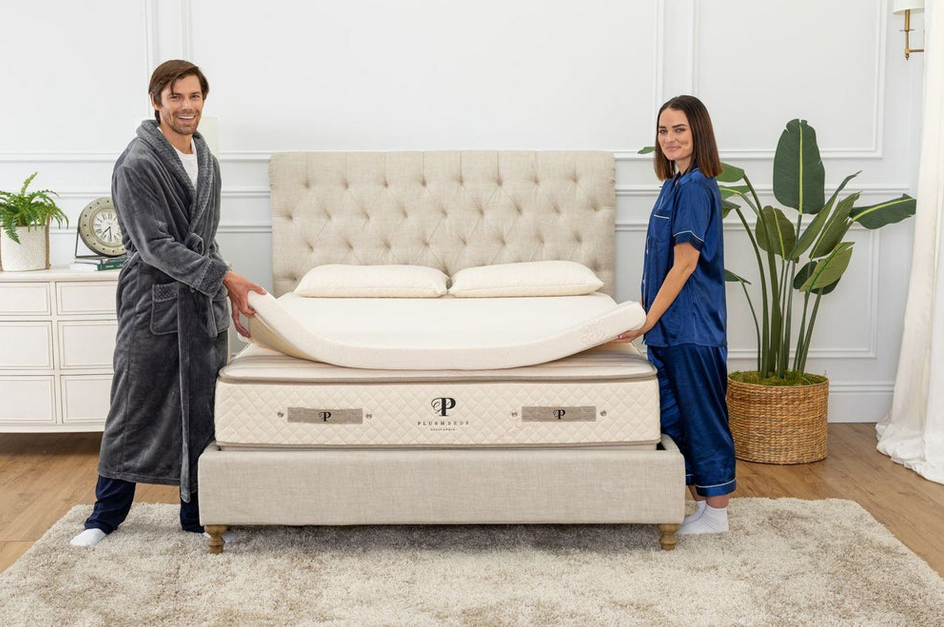 husband and wife placing a latex mattress topper on bed